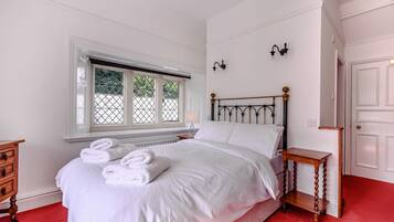 A bedroom with a bed, a window, a nightstand, a dresser, and a door.