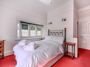 A bedroom with a bed, a window, a nightstand, a dresser, and a door.