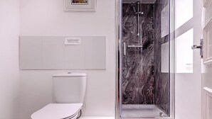 Une salle de bain moderne avec des toilettes, un espace douche et un pare-baignoire en marbre.