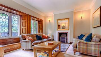 A cozy living room with a fireplace, two sofas, a coffee table, and a bookshelf.