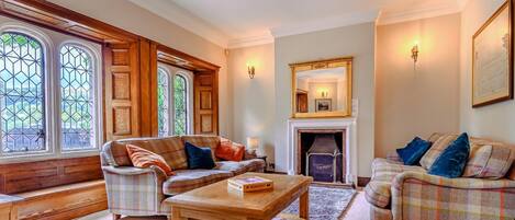 Una sala de estar acogedora con chimenea, dos sofás, una mesa de centro y una estantería.