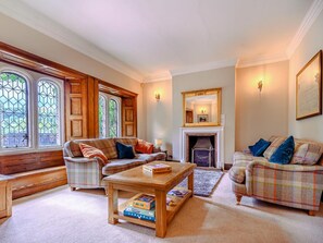 A cozy living room with a fireplace, two sofas, a coffee table, and a bookshelf.