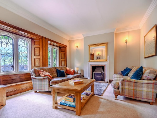 A cozy living room with a fireplace, two sofas, a coffee table, and a bookshelf.