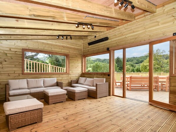 A wooden interior with a sofa set and a view of the outdoors.