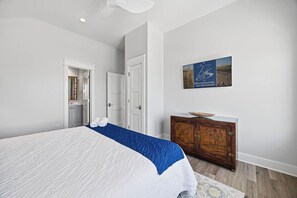 Ein Schlafzimmer mit einem Bett, einem Holzschrank, einem Gemälde und einer Tür zu einem Badezimmer.