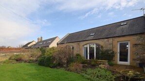 A row of stone houses with a grassy lawn and a clear sky. - 1 Bed in Craster (94372) (Longhoughton)
