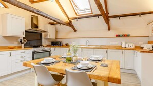 A modern kitchen with white cabinets, a wooden dining table, and a skylight. - 2 Bed in Umberleigh  (88605) (Chittlehampton)