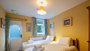 A hotel room with two beds, a door with a frosted glass panel, a window with curtains, and a ceiling light. - 2 Bed in Hawkshead (oc-llh12) (Claife)