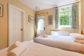 Habitación de hotel con dos camas, una ventana con cortinas, un radiador y una puerta.