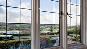 A room with large windows offering a view of a lake and surrounding landscape. - 2 Bed in Hawkshead (oc-llh12) (Claife)