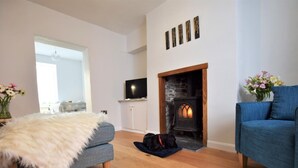 Ein Wohnzimmer mit Kamin, einer Couch, einem Fellteppich und einem Fernseher.