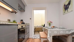 A modern kitchen with a built-in oven, a dining table with a white tablecloth, and a view of the outside.