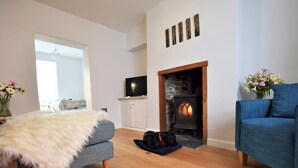 A living room with a fireplace, a sofa, a fur throw, and a TV.