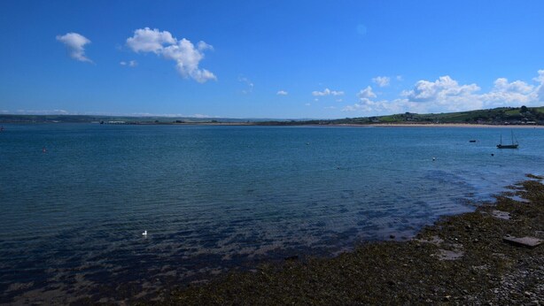 A coastal scene with calm water, a sandy beach, and a small boat.