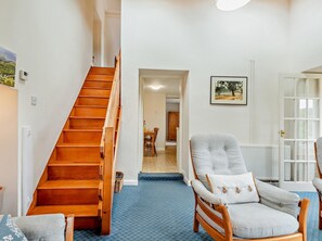 Eine Treppe führt zu einem Essbereich, ein Stuhl mit einem Bienenkissen und ein gerahmtes Bild an der Wand.