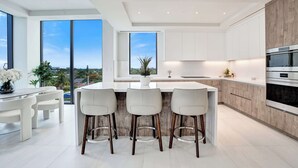 Una cocina moderna con una isla grande, taburetes de bar y vistas a la ciudad.