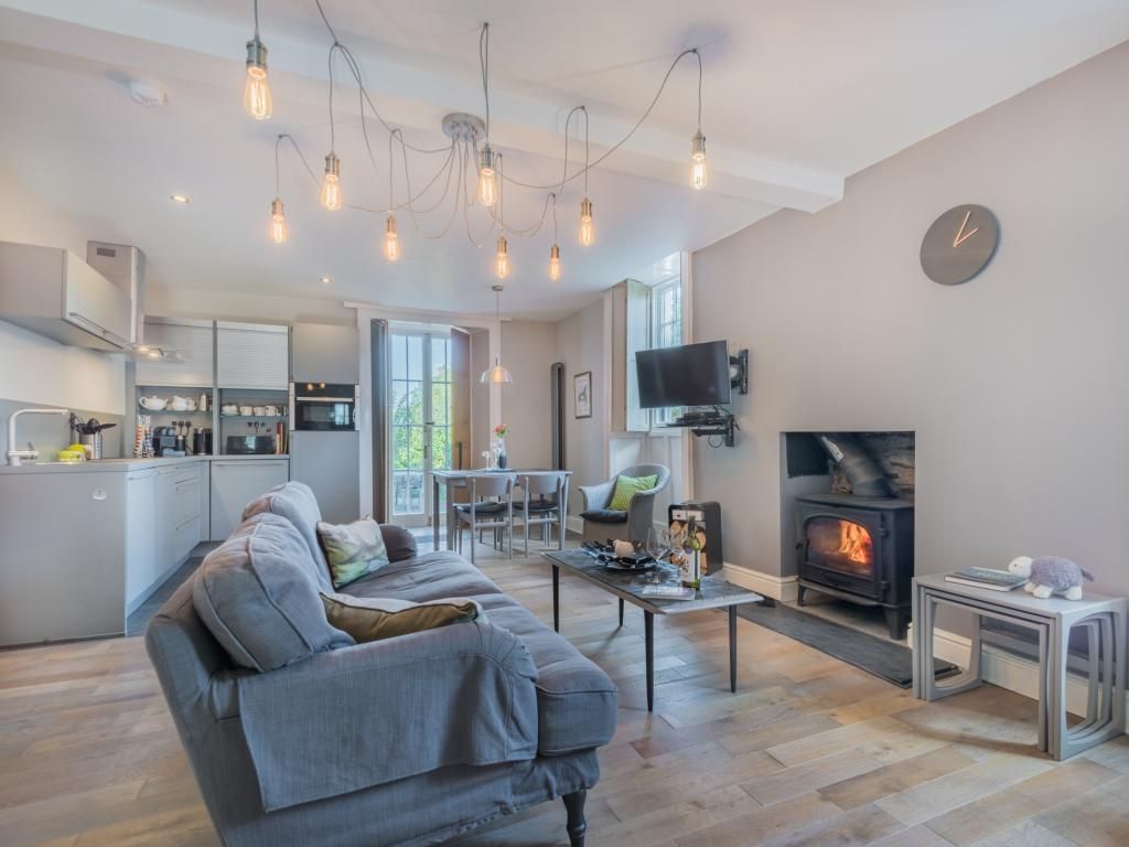 A modern living room with a sofa, a fireplace, a television, and a kitchen in the background.