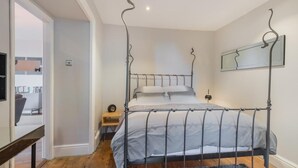 A four-poster bed with a metal frame, a small bedside table, a chair, and a rug. - 1 Bed in Coniston Lake (SZ402) (Blawith)
