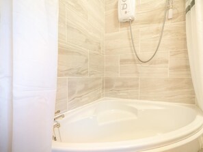 A bathroom with a bathtub, a showerhead, and a wall-mounted control panel. - 4 Bed in Windermere (oc-93832) (Bowness on Windermere)