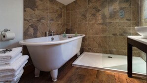 Une salle de bain avec une baignoire sur pieds, un espace douche et un lavabo.