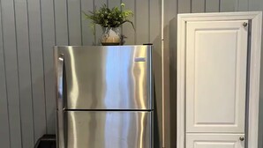 A stainless steel refrigerator with a freezer compartment, a small black appliance, and a white cabinet against a grey wall. - Entire rental, Adama Suites St John’s Antigua (Potters Village)