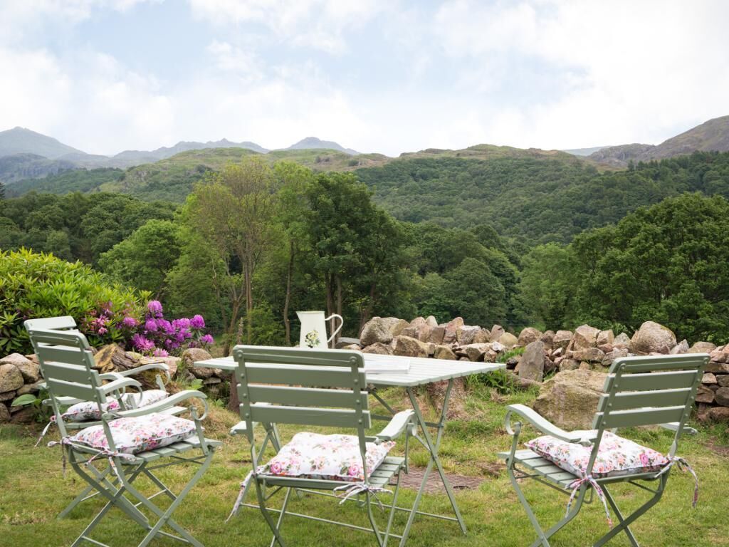 A garden with outdoor seating and a view of a mountainous landscape.