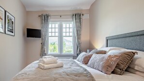A bedroom with a bed, pillows, a TV, and a window with curtains. - 4 Bed in Cockermouth (oc-91210) (Wythop)