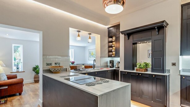 A modern kitchen with a central island, dark cabinetry, and pendant lighting. - 4 Bed in Cockermouth (oc-91210) (Wythop)