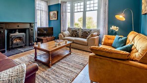A living room with a fireplace, sofa, coffee table, and a television. - 4 Bed in Cockermouth (oc-91210) (Wythop)