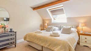 Ein Schlafzimmer mit Bett, Nachttischen, einem Schminktisch und einem Oberlicht.