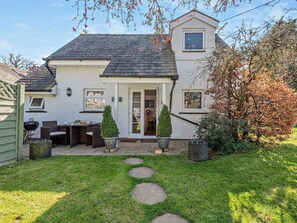 Ein Haus mit Terrasse, Grill und kleinem Garten.