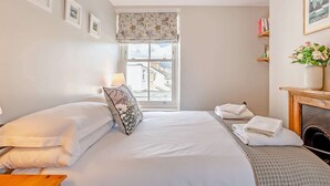 Ett hotellrum med en säng, ett fönster med utsikt, en lampa och en öppen spis.