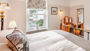 A bedroom with a large bed, a window with a view, a bedside table, a mirror, and a lamp. - 2 Bed in Keswick (oc-93224) (Keswick)