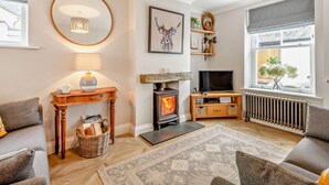 A cozy living room with a fireplace, a television, and a large window with a view. - 2 Bed in Keswick (oc-93224) (Keswick)