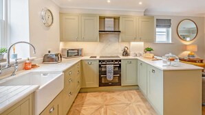 A modern kitchen with a central island, built-in oven, microwave, and a kettle. - 2 Bed in Keswick (oc-93224) (Keswick)