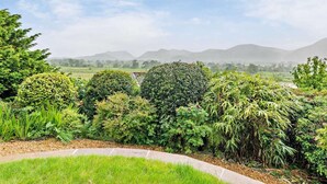 A landscaped garden with various plants and a view of distant hills. - 3 Bed in Underskiddaw (oc-sz377) (Underskiddaw)