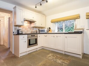 A kitchen with white cabinets, a microwave, a toaster, and a window with a yellow valance. - 2 Bed in Keswick (oc-sz330) (Saint John's Castlerigg and Wythburn)