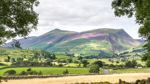 A rural landscape with rolling hills, a stone wall, and a road. - 2 Bed in Keswick (oc-sz330) (Saint John's Castlerigg and Wythburn)