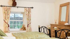 Un dormitorio con dos camas, una ventana con cortinas, un tocador y un espejo.