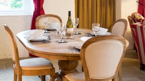 Una mesa de comedor redonda de madera con seis sillas, una botella de vino y varias copas de vino.