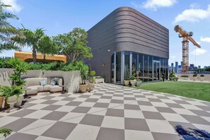A modern building with a checkered floor, outdoor seating, and potted plants. - Nomad (Miami)