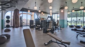 Ett gym med träningsutrustning, stora fönster och hängande lampor.