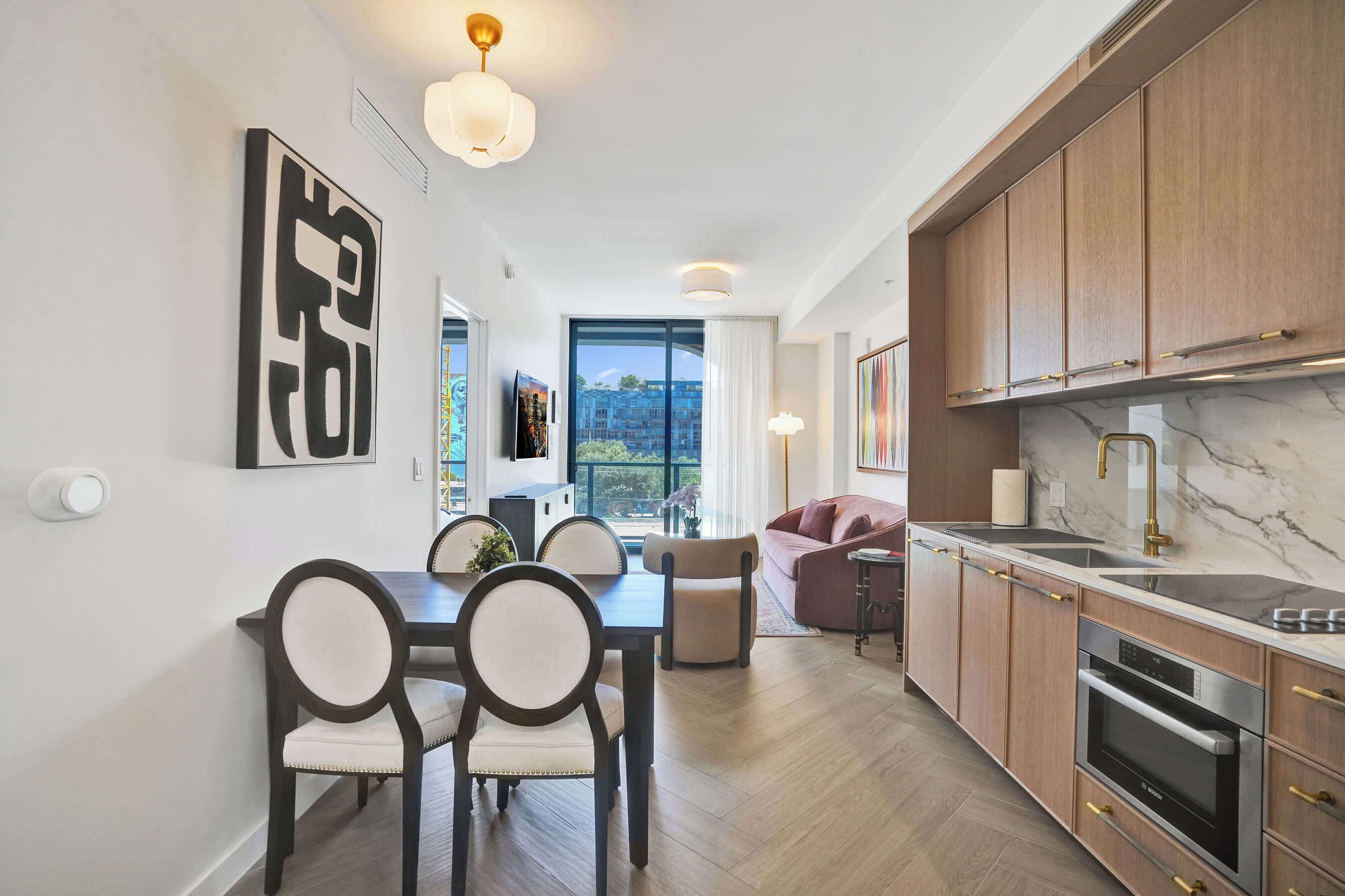 A modern kitchen with wooden cabinets, a marble countertop, and stainless steel appliances.
