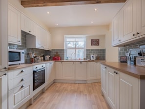 A kitchen with white cabinets, a microwave, an oven, and a window. - 2 Bed in Eden Valley (SZ455) (Warcop)