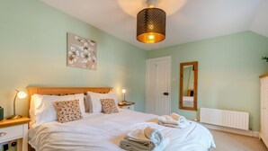 Ein Schlafzimmer mit einem großen Bett, Nachttischlampen, einem Spiegel und einer Heizung.