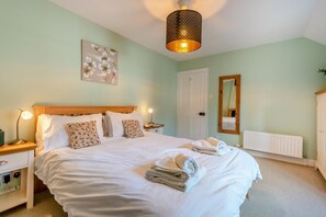A bedroom with a large bed, bedside lamps, a mirror, and a radiator. - 3 Bed in Keswick (oc-sz542) (Keswick)