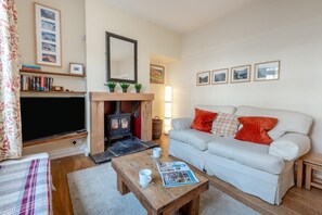 A cozy living room with a fireplace, a sofa, a coffee table, and a bookshelf. - 3 Bed in Keswick (oc-sz542) (Keswick)