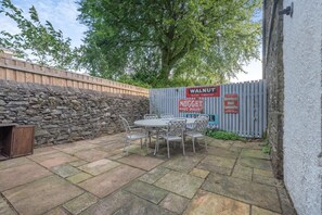 An outdoor patio area with stone flooring, metal chairs, and a table. - 3 Bed in Keswick (oc-sz542) (Keswick)