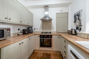 A compact kitchen with a microwave, coffee maker, stove, oven, and a knife rack. - 3 Bed in Keswick (oc-sz542) (Keswick)