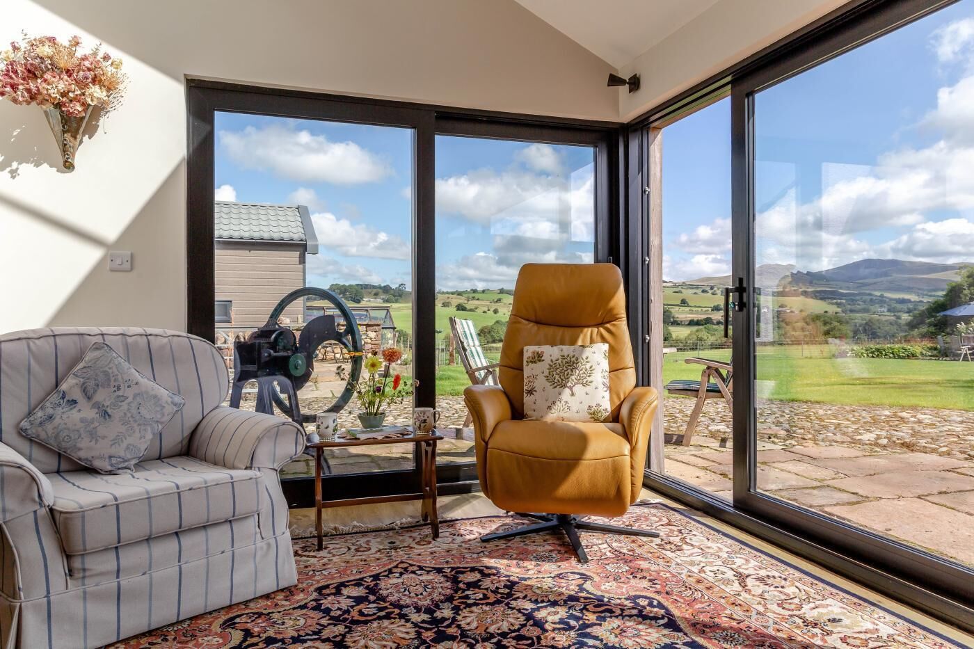 Ein Zimmer mit großem Fenster, einer Couch, einem Sessel und einem Tisch mit einer Dekoration.